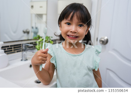 girl child brushing teeth in bathroom girl child brushing teeth in bathroom 135350634