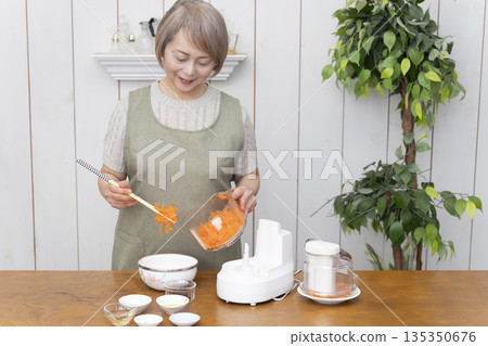 Senior woman cooking using a food processor in the kitchen Senior woman cooking using a food processor in the kitchen 135350676