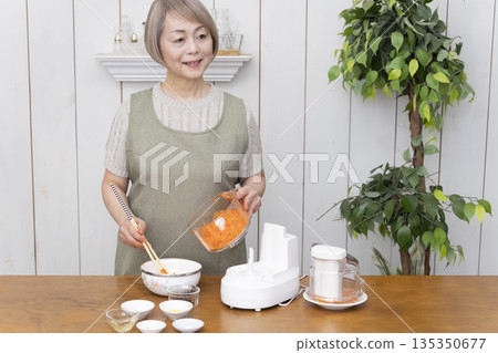 Senior woman cooking using a food processor in the kitchen Senior woman cooking using a food processor in the kitchen 135350677