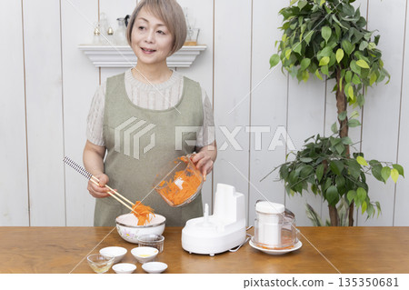Senior woman cooking using a food processor in the kitchen 135350681