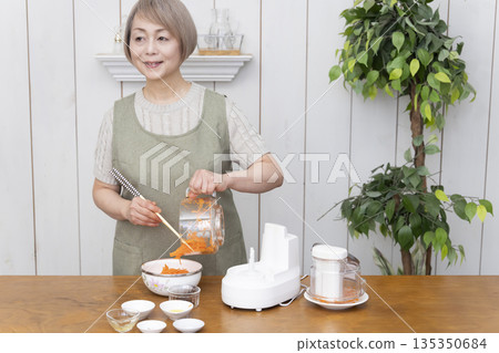Senior woman cooking using a food processor in the kitchen 135350684