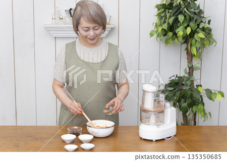Senior woman cooking using a food processor in the kitchen 135350685