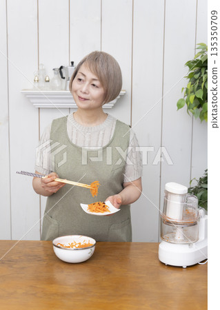 Senior woman cooking using a food processor in the kitchen Senior woman cooking using a food processor in the kitchen 135350709