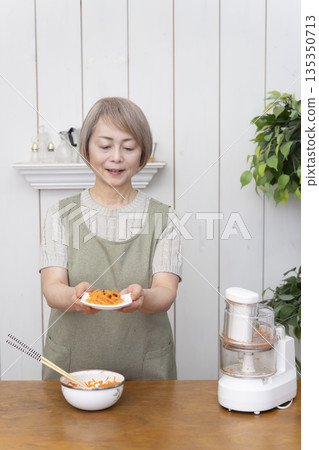 Senior woman cooking using a food processor in the kitchen 135350713