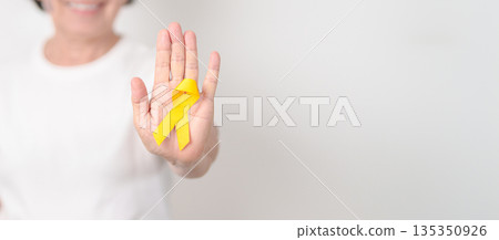 Elderly with Yellow Ribbon for concept of yellow September, Suicide prevention day, Childhood, July Sarcoma, March Endometriosis awareness month , support survivor. Healthcare and World Cancer day 135350926