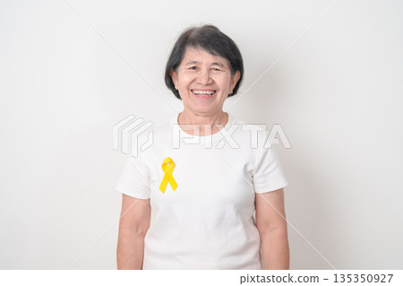 Elderly with Yellow Ribbon for concept of yellow September, Suicide prevention day, Childhood, July Sarcoma, March Endometriosis awareness month , support survivor. Healthcare and World Cancer day 135350927