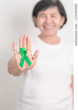 Elderly with Green Ribbon for concept of March world Bipolar disorder day, Cerebral Palsy Awareness month, kidney disease Cancer and Traumatic Brain Injury, TBI. Healthcare and world cancer day 135350993