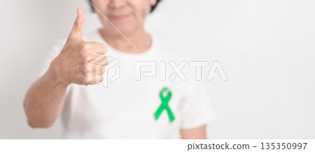 Elderly with Green Ribbon for concept of March world Bipolar disorder day, Cerebral Palsy Awareness month, kidney disease Cancer and Traumatic Brain Injury, TBI. Healthcare and world cancer day Elderly with Green Ribbon for concept of March world Bipolar disorder day, Cerebral Palsy Awareness month, kidney disease Cancer and Traumatic Brain Injury, TBI. Healthcare and world cancer day 135350997