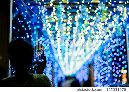 [Tobishima Village, Aichi Prefecture] A woman takes a photo of the spectacular view of wind chimes and illuminations with her smartphone at Tobishima Yoi Akari 135351076