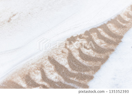 A trench in frozen sand covered with white snow, beach ground of Baltic Sea coast 135352393