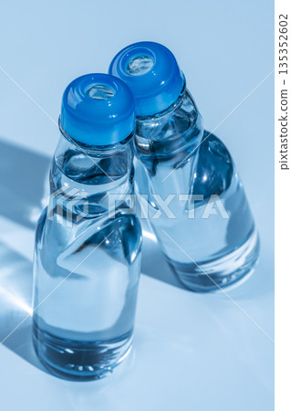 兩瓶裝有彈珠的玻璃瓶裝彈珠,在藍色的光影中排列。 兩瓶裝有彈珠的玻璃瓶裝彈珠,在藍色的光影中排列。 135352602