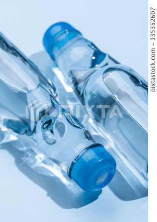 一瓶裝有彈珠的玻璃瓶裝彈珠汽水,靜靜地躺在藍色的光影中。 一瓶裝有彈珠的玻璃瓶裝彈珠汽水,靜靜地躺在藍色的光影中。 135352607