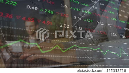 Typing hands inputting trading data on laptop keyboard at office desk, with tablet, potted plant 135352736