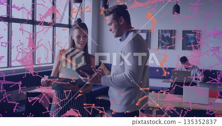 Teen and male collaborators reviewing and pointing at tablet in coworking space, with green folder 135352837