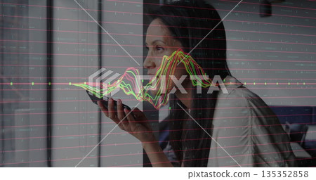 Issuing voice command woman holding smartphone by window at home office, with analytics overlay 135352858