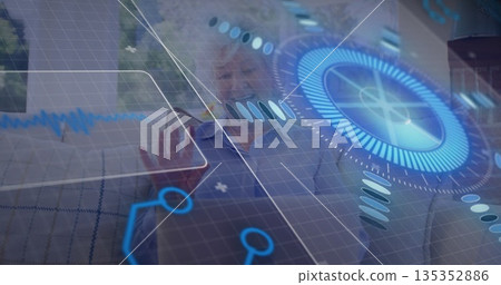 Reaching senior woman touching holographic controls on sofa in living room, with graphs Reaching senior woman touching holographic controls on sofa in living room, with graphs 135352886