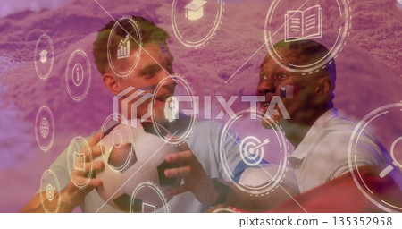 Standing two men wearing polo shirts in studio, holding soccer balls with digital icons Standing two men wearing polo shirts in studio, holding soccer balls with digital icons 135352958