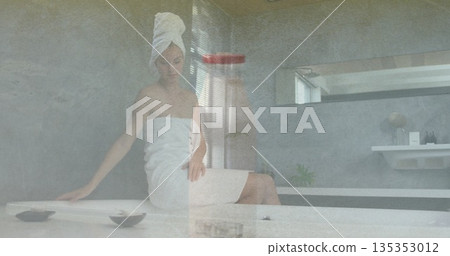 Sitting spa guest adjusting towel turban on head at spa bathroom marble bench, with shallow bowls Sitting spa guest adjusting towel turban on head at spa bathroom marble bench, with shallow bowls 135353012