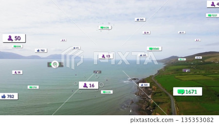 Floating digital overlay icons hovering over narrow coastal road by rocky shoreline, green fields 135353082