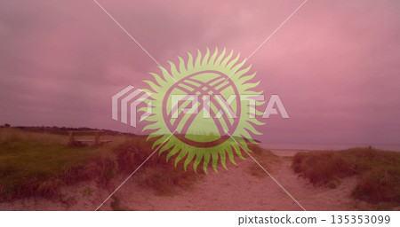 Sandy pathway winding through grassy dunes toward shore with wooden bench and stylized sun emblem 135353099