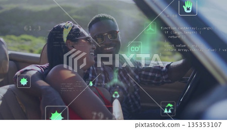 Smiling couple driving convertible car on rural road, with colorful headscarf and sunglasses 135353107