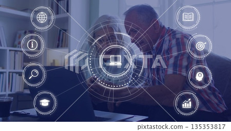 Studying senior couple exploring online network concepts at desk, with laptop smartphone icons Studying senior couple exploring online network concepts at desk, with laptop smartphone icons 135353817