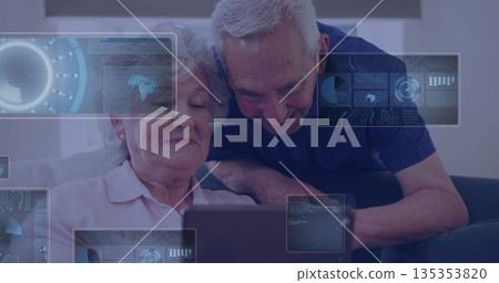 Exploring senior couple interacting with tablet on living room sofa, with digital overlay graphics 135353820