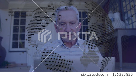 Sitting senior man wearing shirt using laptop on porch, with globe overlay, wicker chair and plant 135353836