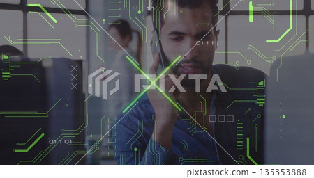 Talking man in denim shirt using phone at office desk, monitors and tech graphics, copy space 135353888