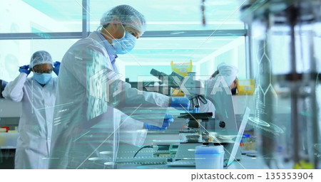Examining male scientist peering into trinocular microscope at lab bench, with protective gear Examining male scientist peering into trinocular microscope at lab bench, with protective gear 135353904