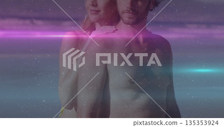 Posing shirtless man and woman creating digital portrait in studio, with neon light streaks 135353924