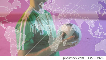 Holding soccer ball, male soccer player wearing green jersey standing in studio with world map 135353926