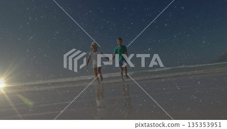 Running siblings holding hands barefoot at wet sandy beach at low tide, with straw sun hat 135353951