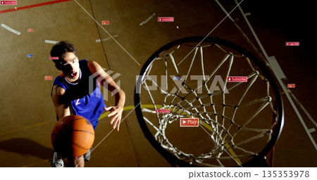 Leaping basketball player in blue jersey dunking ball at gym court, with overlay icons, copy space 135353978