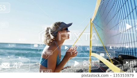 Kneeling athlete in sports-bra on beach facing yellow border volleyball net with icons, copy space 135353979