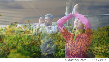 Standing yoga partners holding hands in prayer pose wearing pink jacket and gray hoodie on veranda Standing yoga partners holding hands in prayer pose wearing pink jacket and gray hoodie on veranda 135353994