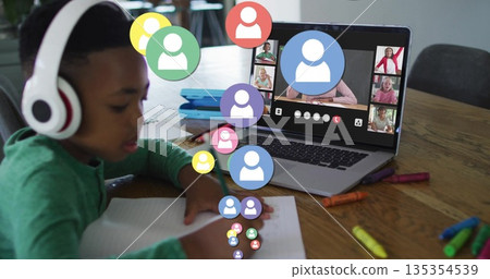 Writing boy wearing green shirt and headphones noting in notebook at home, with laptop, copy space Writing boy wearing green shirt and headphones noting in notebook at home, with laptop, copy space 135354539