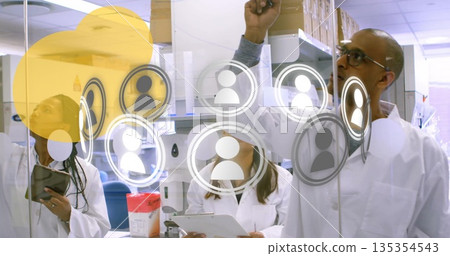 Collaborating three scientists in lab coats discussing user icons on glass board in lab with tablet Collaborating three scientists in lab coats discussing user icons on glass board in lab with tablet 135354543