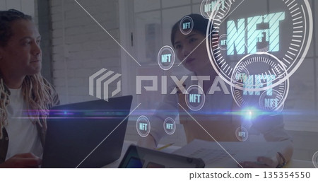 Colleagues in button-down shirts discussing NFT with laptop and documents in office, with NFT icons 135354550