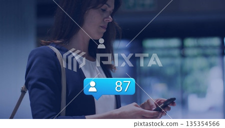 Woman checking smartphone with tan shoulder bag in lobby, blue notification showing 87, copy space Woman checking smartphone with tan shoulder bag in lobby, blue notification showing 87, copy space 135354566