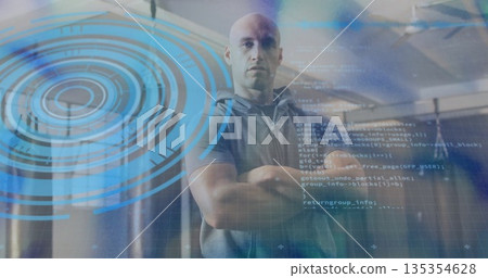 Standing bald male crossing arms in data center, with server racks and holographic code displays 135354628