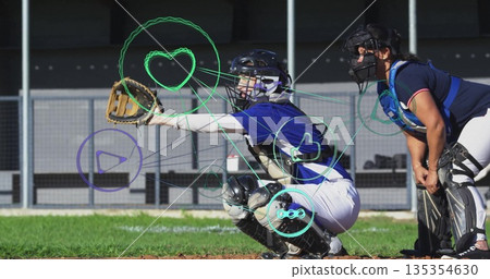 Squatting catcher wearing chest protector and helmet extending mitt to catch baseball at home plate Squatting catcher wearing chest protector and helmet extending mitt to catch baseball at home plate 135354630