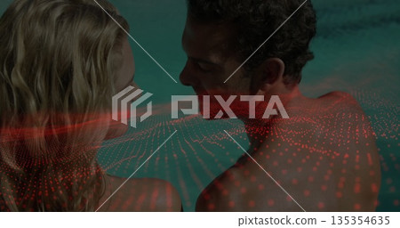 Standing couple gazing at each other in turquoise pool water, with red digital dot grid overlay Standing couple gazing at each other in turquoise pool water, with red digital dot grid overlay 135354635