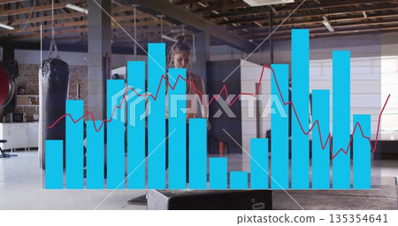 Jumping female athlete in sports bra and leggings performing box jump in gym with graph overlay Jumping female athlete in sports bra and leggings performing box jump in gym with graph overlay 135354641