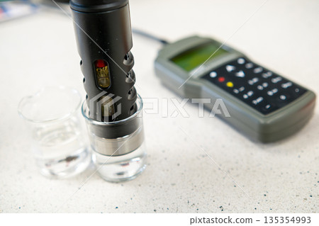 pH electrode placed in a glass of water, concept of water quality testing and analysis. pH electrode placed in a glass of water, concept of water quality testing and analysis. 135354993