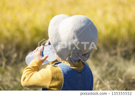 A girl hydrates while sitting with rice fields in the background 135355552