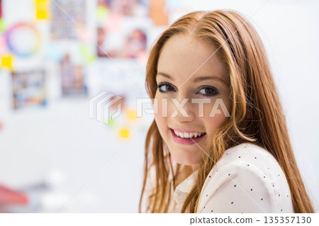 Woman in her twenties smiling in polka dot blouse beside sticky note wall pictures, copy space 135357130