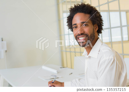 African American man holding pen above paper while sitting at modern office desk, copy space 135357215