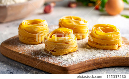 Fresh pasta nests arranged on a board with visible flour texture, highlighting handmade cuisine 135357280