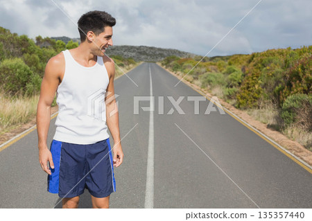 Man wearing sportswear pausing on paved road shoulder by scrub brush with center line, copy space Man wearing sportswear pausing on paved road shoulder by scrub brush with center line, copy space 135357440